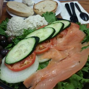 A plate of salmon, cucumbers, tomatoes and bread.