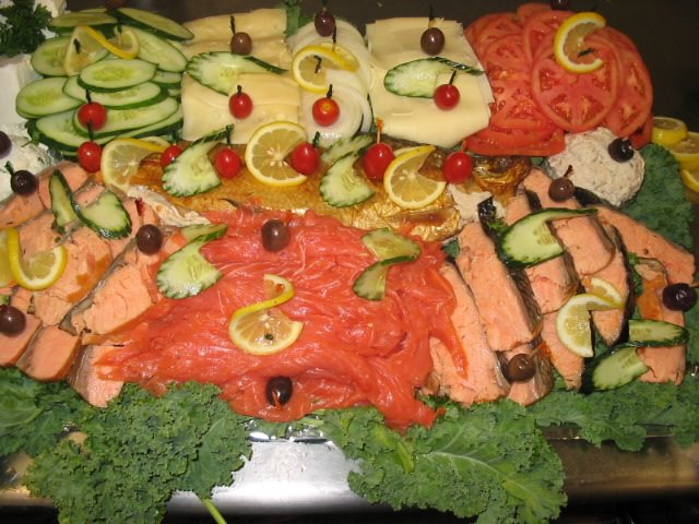 A platter of salmon, cucumbers, tomatoes and other vegetables.