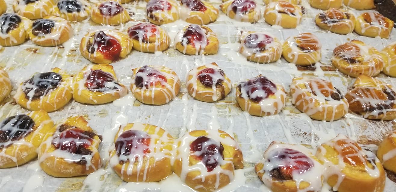 A tray of pastries with icing and fruit on it.