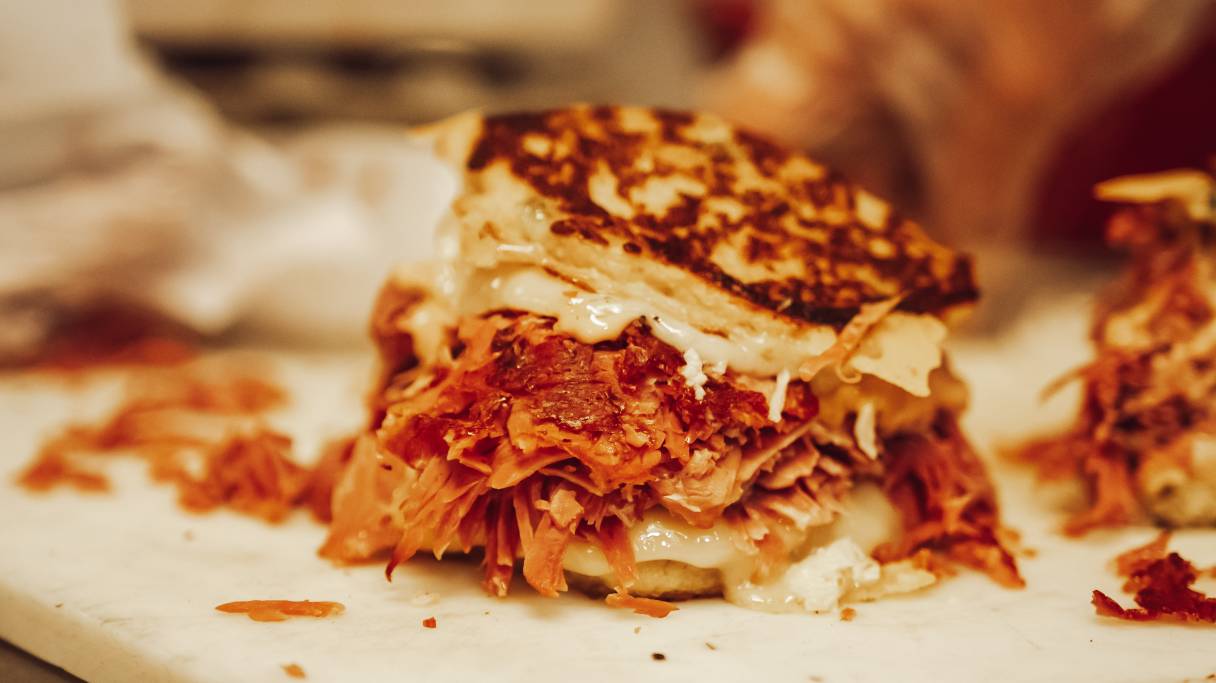 A sandwich with meat and cheese on a cutting board.